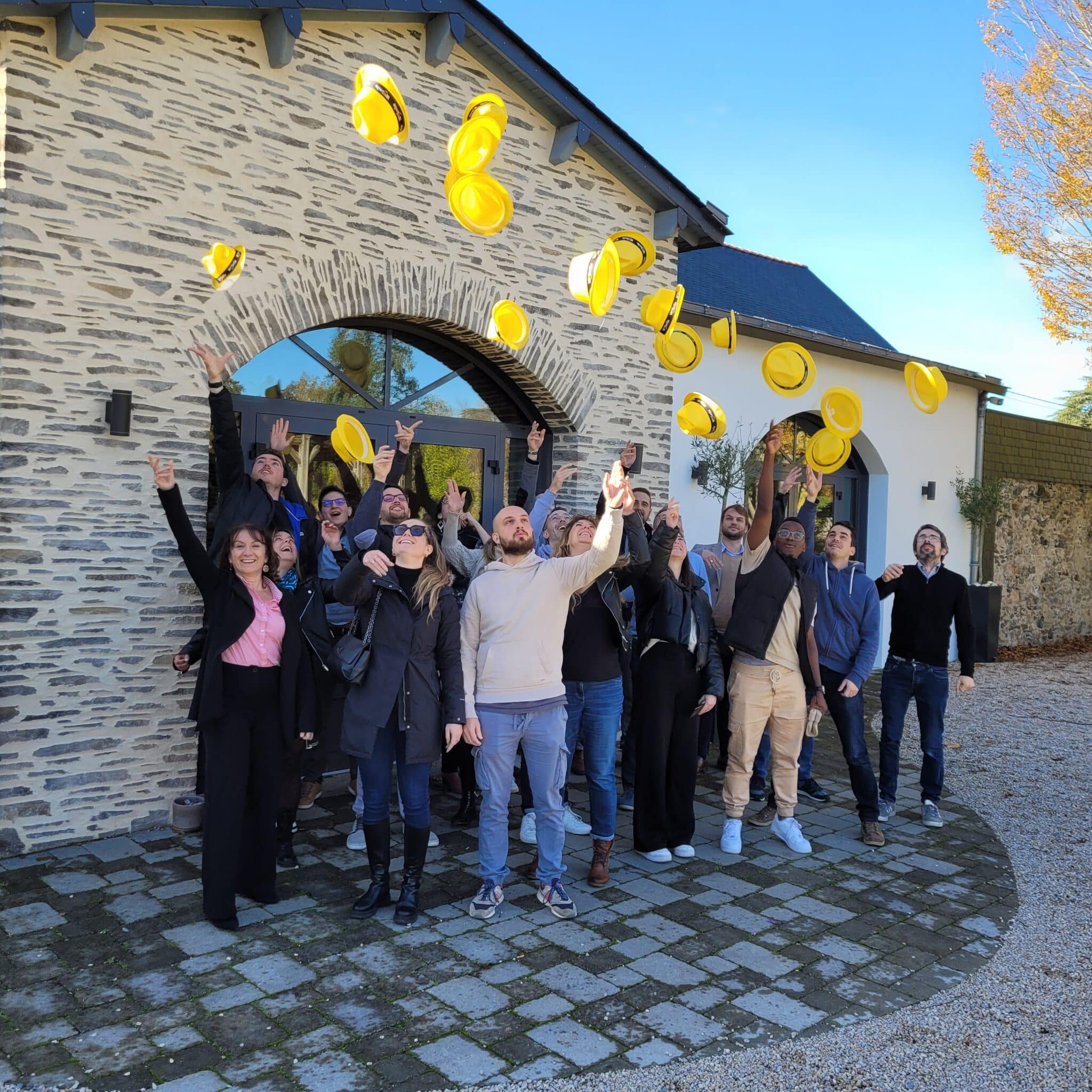 Groupe de personnes lançant des chapeaux jaunes.